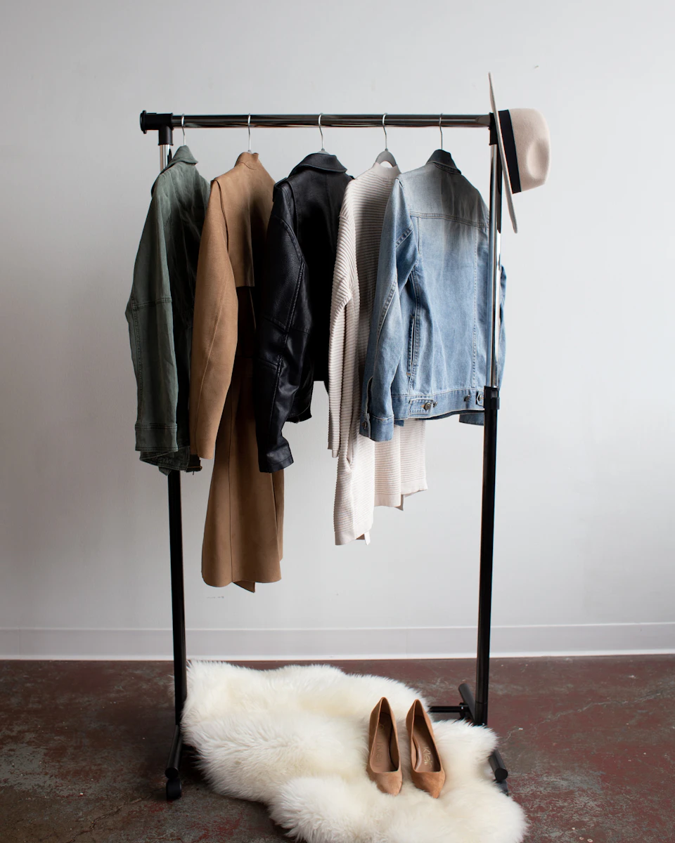 A considered wardrobe of jackets, knitwear, and accessories on a rail.